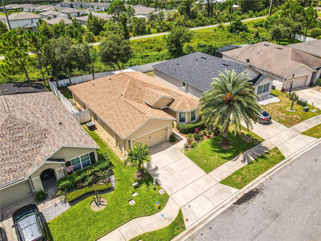 An aerial view shows three suburban houses with shingled roofs, driveways, and green lawns — 2672 STAR CORAL LANE, NEW SMYRNA BEACH, FL