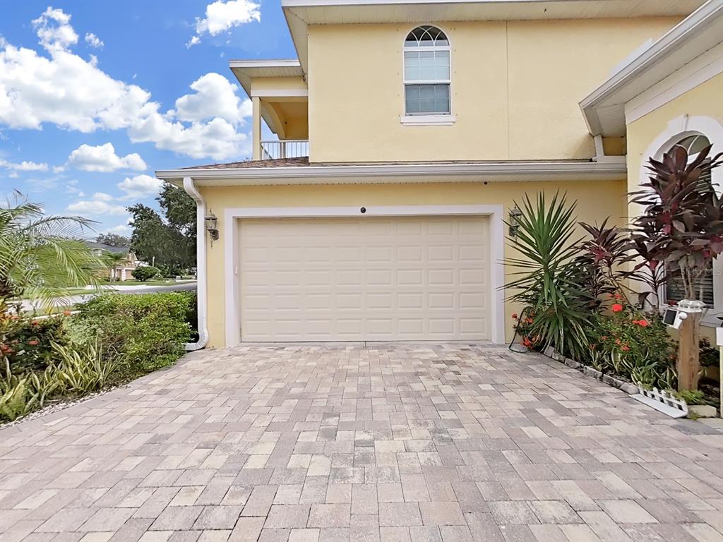 A beige two-story house features a two-car garage and a paved driveway with landscaping — 1312 FISHING LAKE DRIVE, ODESSA, FL