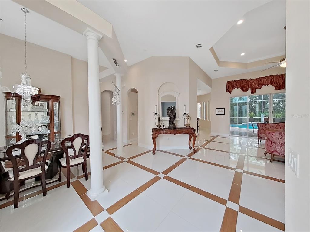 A formal dining area and foyer feature white tiled floors with brown accent borders — 1312 FISHING LAKE DRIVE, ODESSA, FL