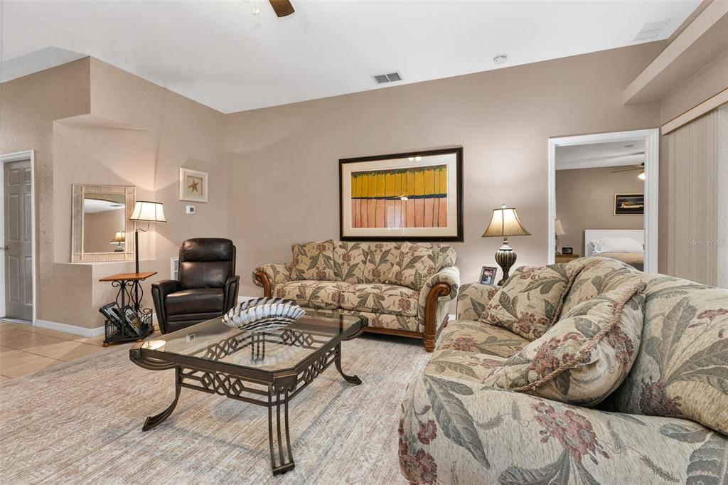 A living room features floral sofas, a glass-topped coffee table, and a leather armchair — 24208 BUCKINGHAM WAY, PUNTA GORDA, FL