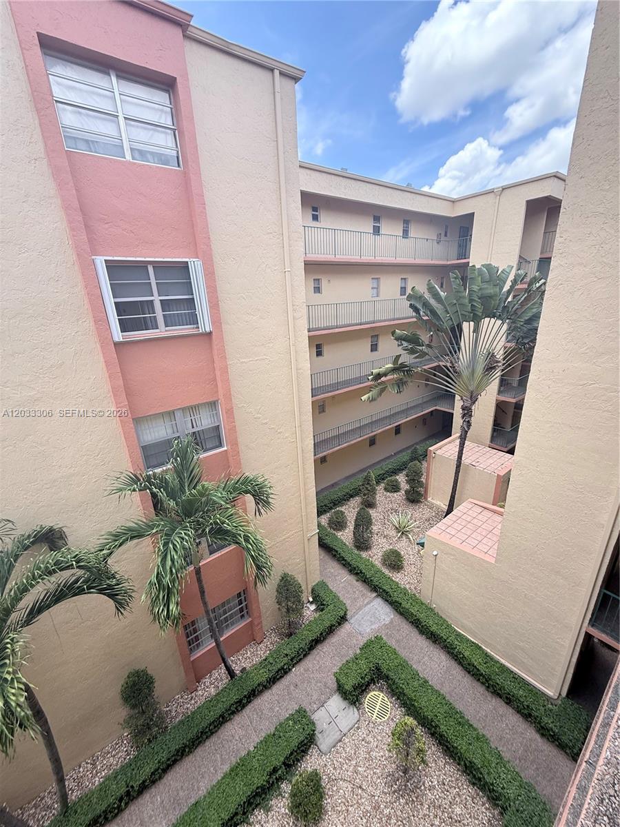 An exterior view of a multi-story apartment complex with a central courtyard and palm trees — 1975 W 44th Pl # 401, Hialeah FL 33012, HIALEAH, FL