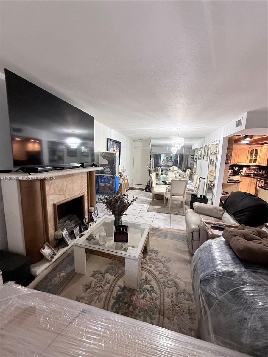 A living room features a fireplace with a large television, tile flooring, and dining area — 1975 W 44th Pl # 401, Hialeah FL 33012, HIALEAH, FL