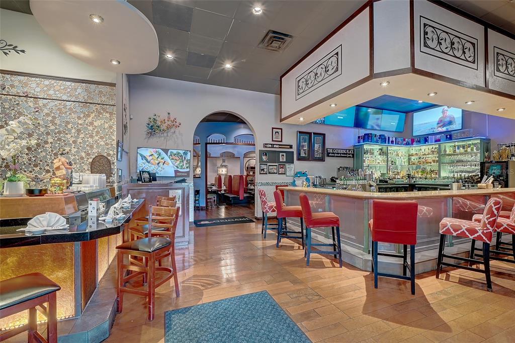 A restaurant interior features a bar with red stools, wood flooring, and an arched entryway — 8911 DANIELS PARKWAY UNIT 5, FORT MYERS, FL