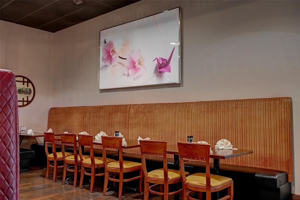 A restaurant dining area features a long banquette, wooden chairs, and floral wall art — 8911 DANIELS PARKWAY UNIT 5, FORT MYERS, FL