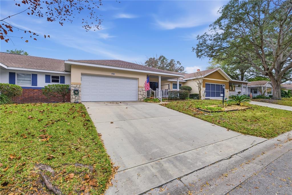 A single-story house with a white garage door, a concrete driveway, and a front porch — 8702 SW 94TH STREET UNIT E, OCALA, FL