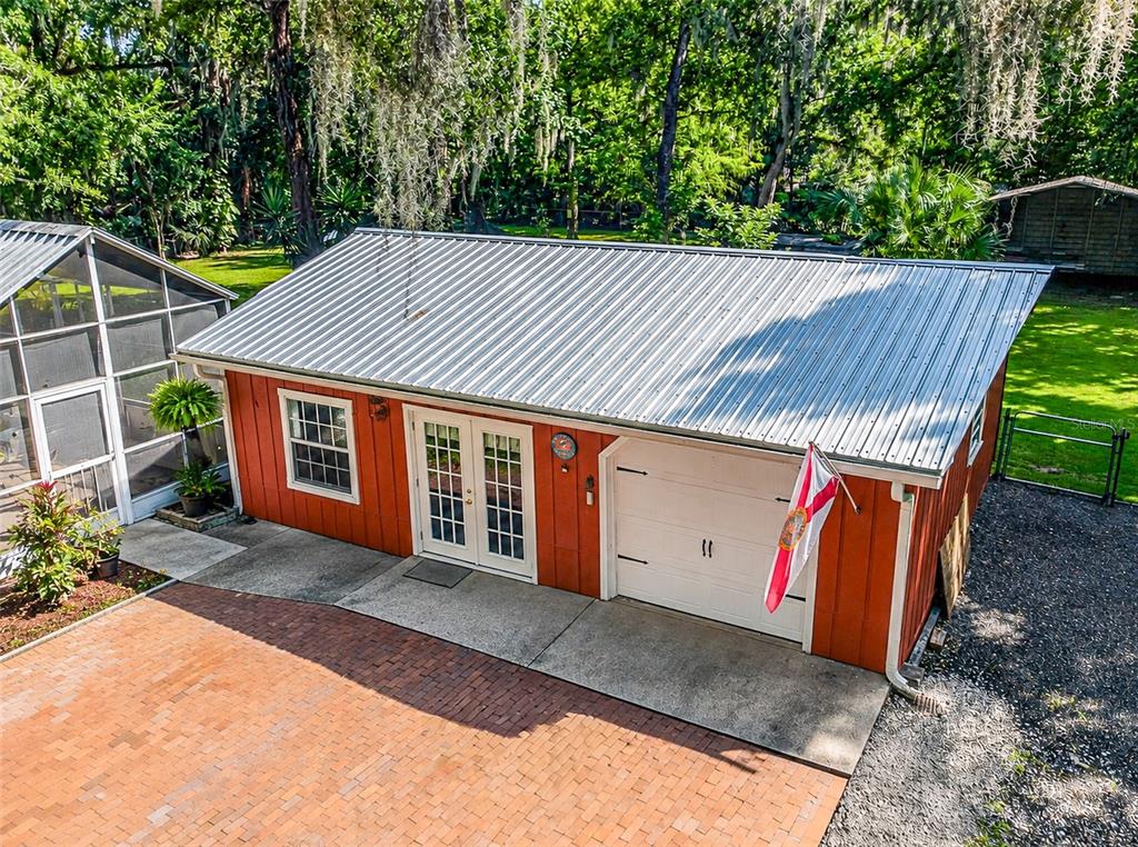 An aerial view shows a red detached garage with a metal roof and double doors — 625 WILDWOOD DRIVE, NEW SMYRNA BEACH, FL