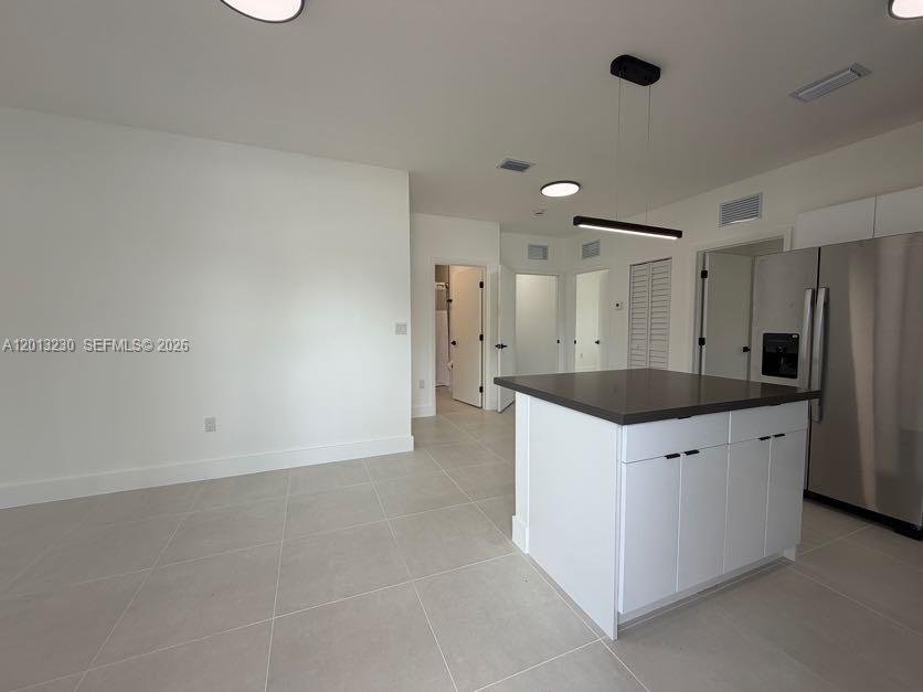 A modern kitchen features a white island with a dark countertop and stainless steel appliances — 1440 NW 61st St # 2, Miami FL 33142, MIAMI, FL