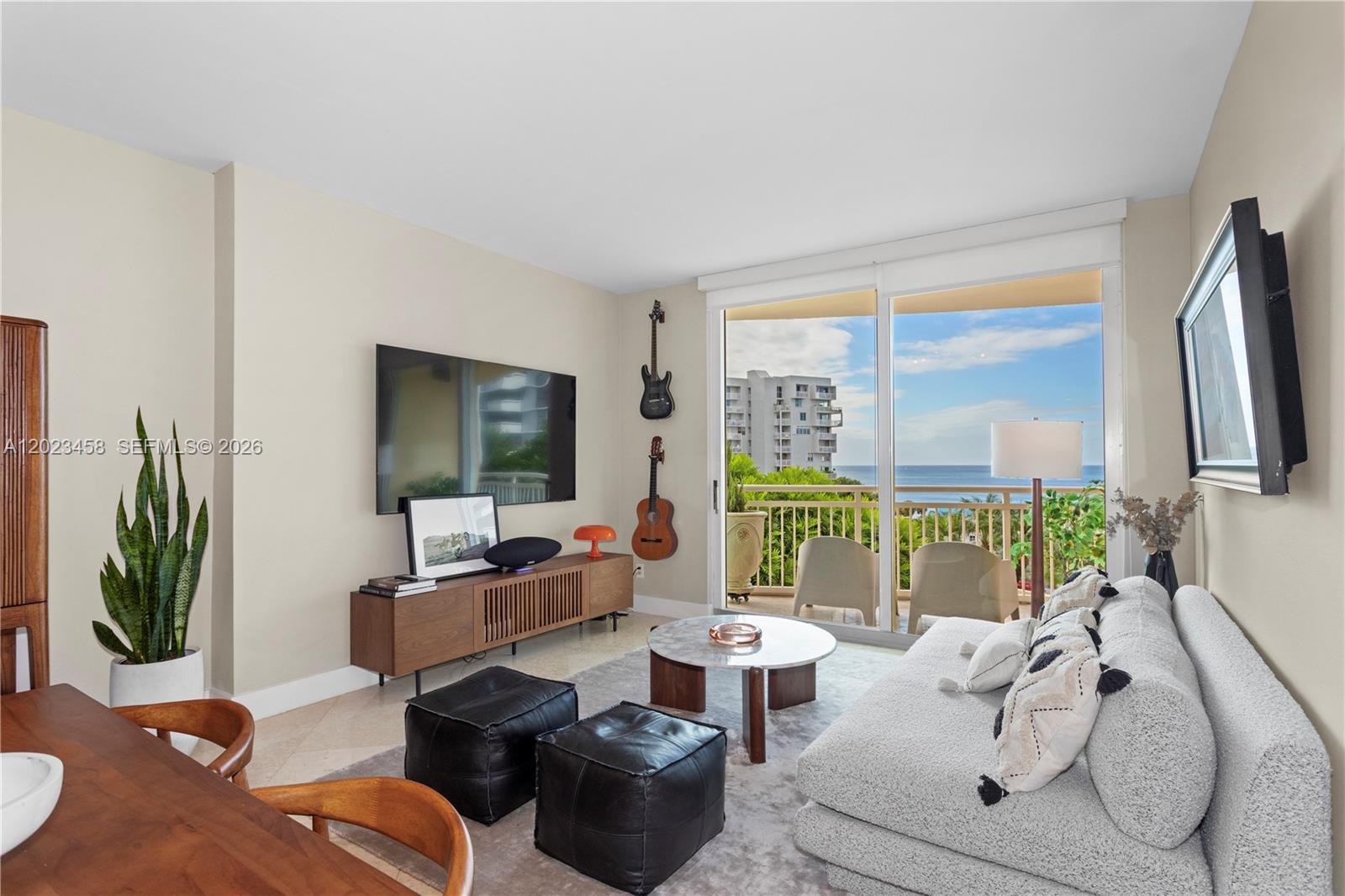 A living room features a television, two guitars, a sofa, and a balcony with ocean views — 2475 Brickell Ave # 708, Miami FL 33129, MIAMI, FL