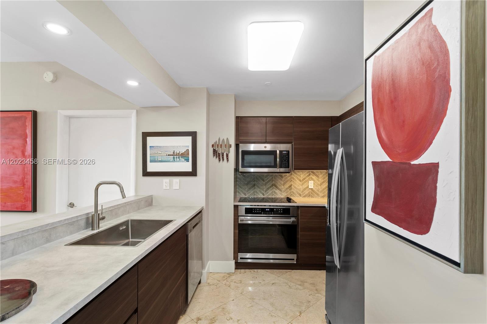 A modern kitchen features dark wood cabinets, stainless steel appliances, and a light stone countertop — 2475 Brickell Ave # 708, Miami FL 33129, MIAMI, FL