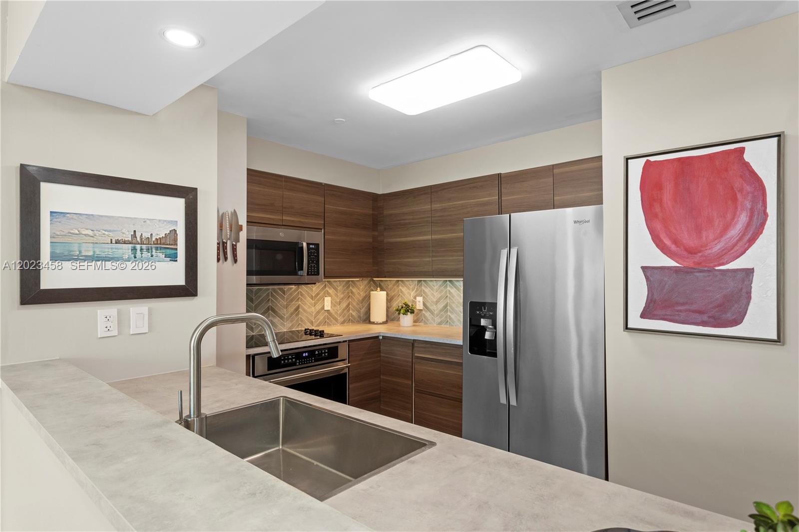 A modern kitchen features wood-grain cabinets, stainless steel appliances, and a gray stone countertop — 2475 Brickell Ave # 708, Miami FL 33129, MIAMI, FL