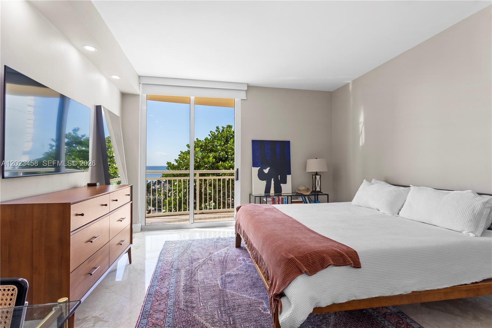 A bedroom features a bed, a wooden dresser, a patterned rug, and a balcony view — 2475 Brickell Ave # 708, Miami FL 33129, MIAMI, FL