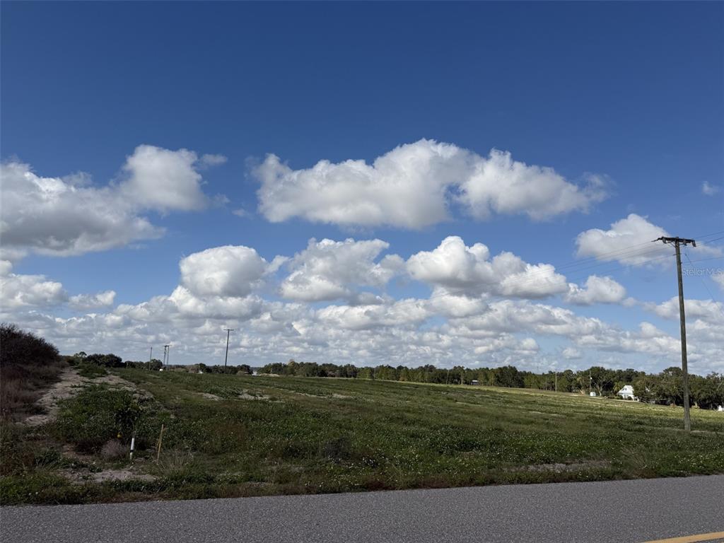 A large, grassy, undeveloped plot of land under a bright blue sky with scattered clouds — 203 SEMINOLE BEACH DRIVE, BABSON PARK, FL