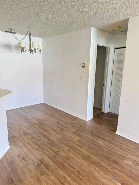 An empty dining area features wood-look flooring, a chandelier, and a doorway to a hallway — 3350 N Pinewalk Dr # 1426, Margate FL 33063, MARGATE, FL