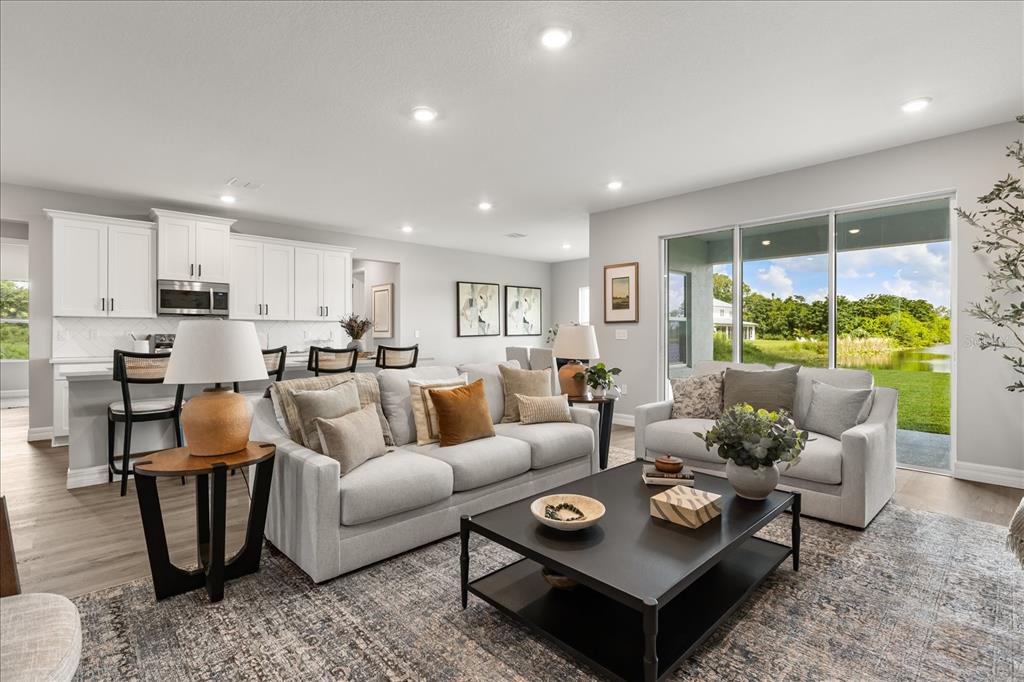 An open-concept living room features a kitchen with white cabinets, a sofa, and sliding doors — 25 FREESIA COURT, HOMOSASSA, FL
