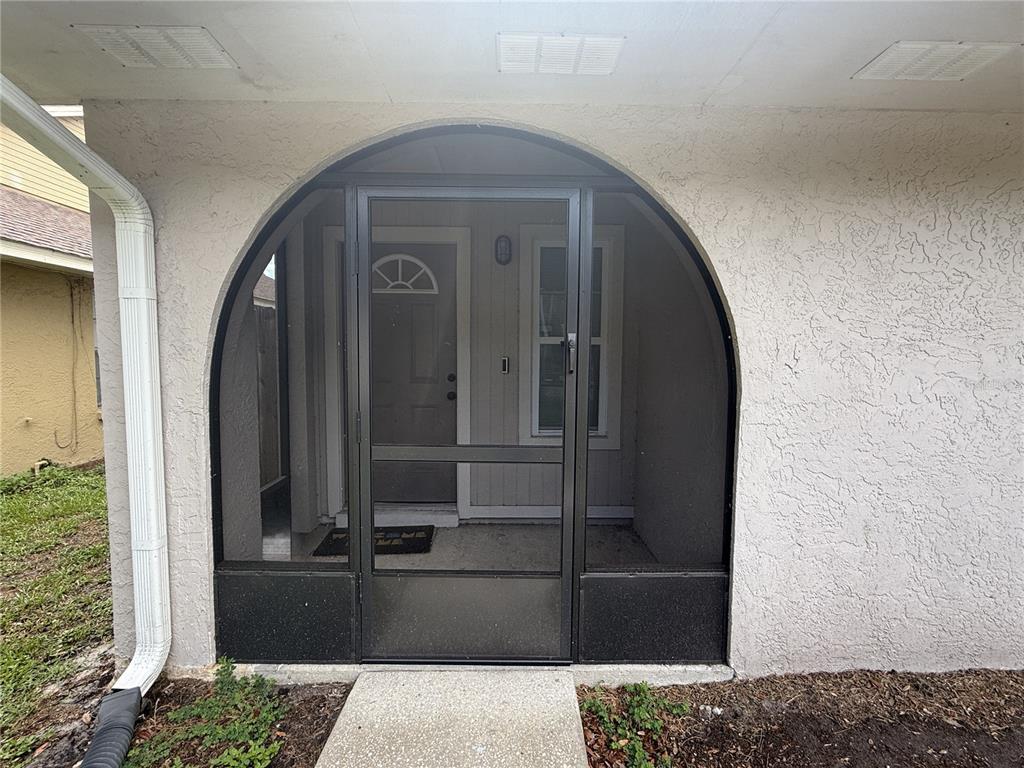A screened-in entryway features an arched frame over a front door and a concrete walkway — 2042 SHADOW PINE DRIVE, BRANDON, FL