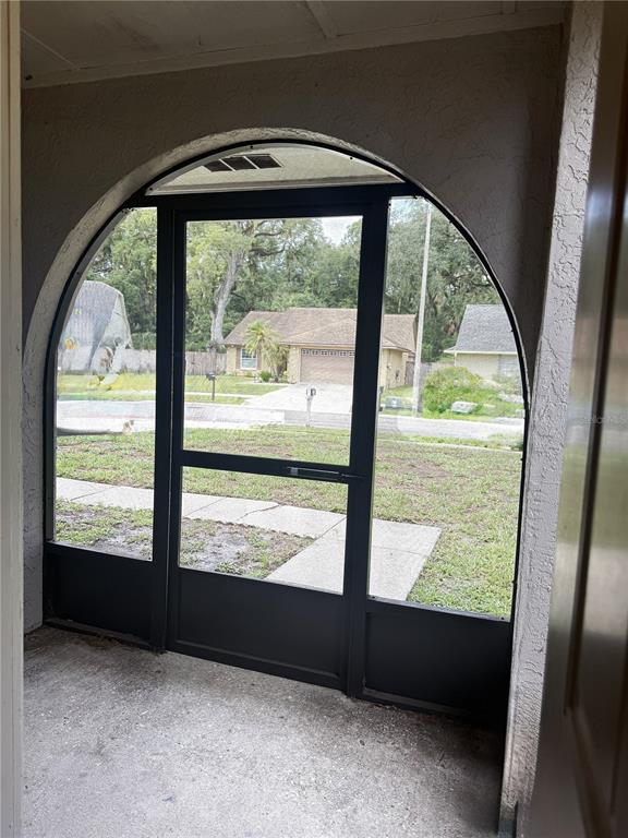A view from a covered porch through an arched screen door toward a suburban street — 2042 SHADOW PINE DRIVE, BRANDON, FL