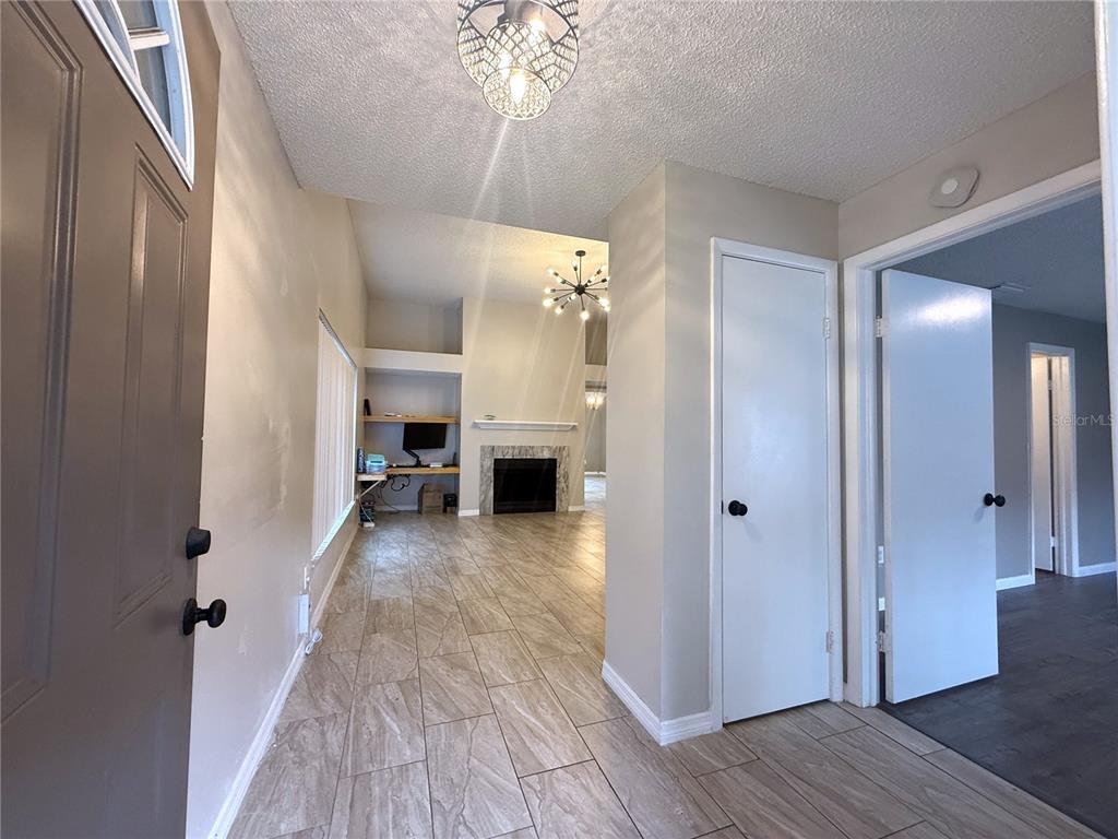 An entryway with tile flooring leads into a living room featuring a fireplace and desk — 2042 SHADOW PINE DRIVE, BRANDON, FL