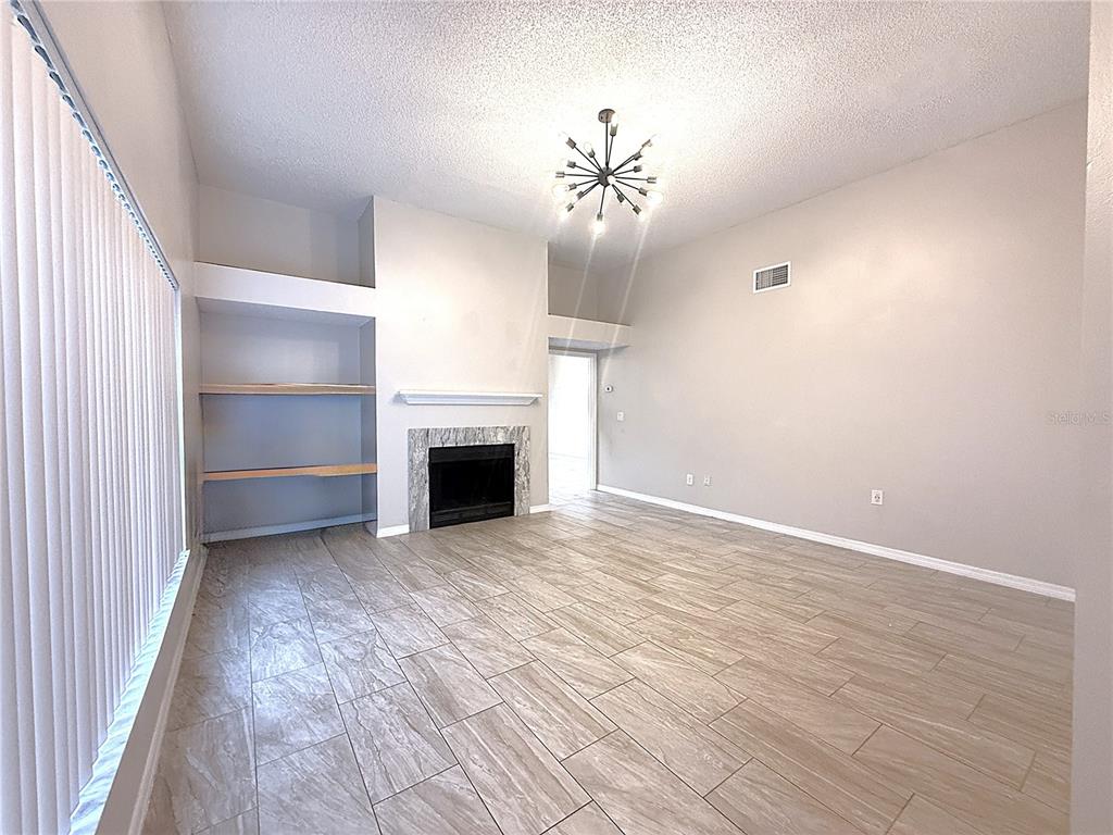 A living room features light tile flooring, a fireplace, built-in shelves, and a modern chandelier — 2042 SHADOW PINE DRIVE, BRANDON, FL
