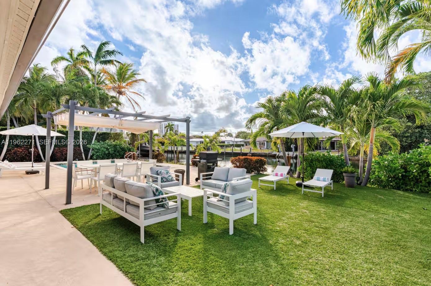 A backyard patio features a pergola, outdoor seating, lounge chairs, and a view of water — 636 Hibiscus Dr # 0, Hallandale Beach FL 33009, HALLANDALE BEACH, FL