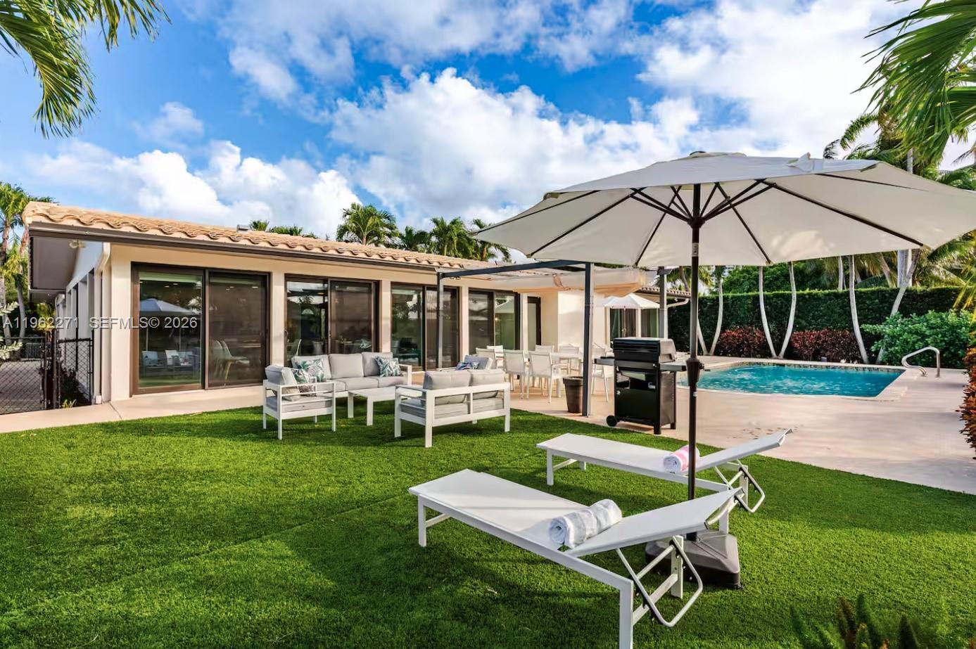 A backyard with a swimming pool, patio furniture, a grill, and lounge chairs on grass — 636 Hibiscus Dr # 0, Hallandale Beach FL 33009, HALLANDALE BEACH, FL