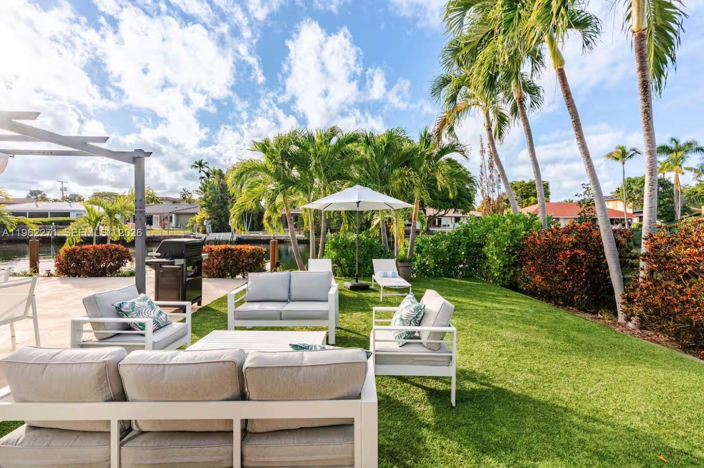 A backyard patio features outdoor furniture, a grill, and palm trees overlooking a canal — 636 Hibiscus Dr # 0, Hallandale Beach FL 33009, HALLANDALE BEACH, FL