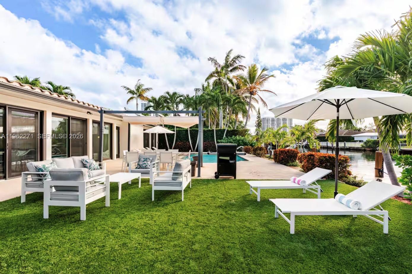 A backyard patio features outdoor seating, lounge chairs, a swimming pool, and a waterfront view — 636 Hibiscus Dr # 0, Hallandale Beach FL 33009, HALLANDALE BEACH, FL