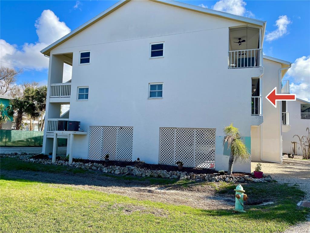 The exterior of a multi-story residential building features white stucco walls, balconies, and lattice panels — 5031 N BEACH ROAD UNIT 116, ENGLEWOOD, FL