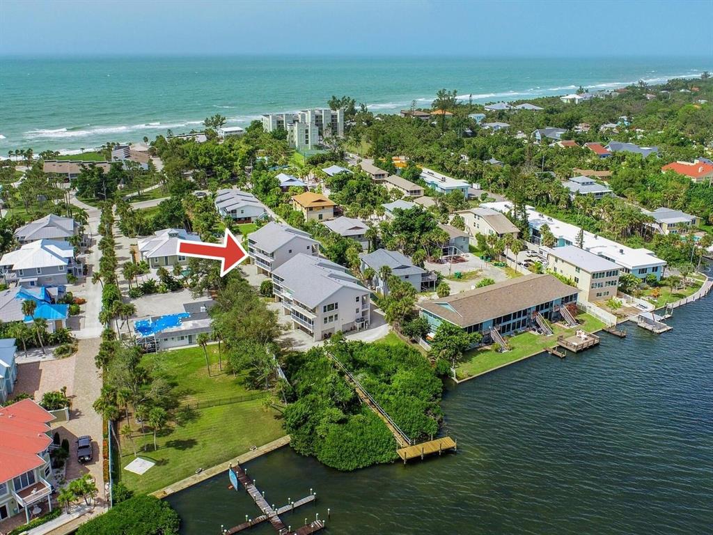 An aerial view shows a multi-story residential building near a body of water — 5031 N BEACH ROAD UNIT 116, ENGLEWOOD, FL