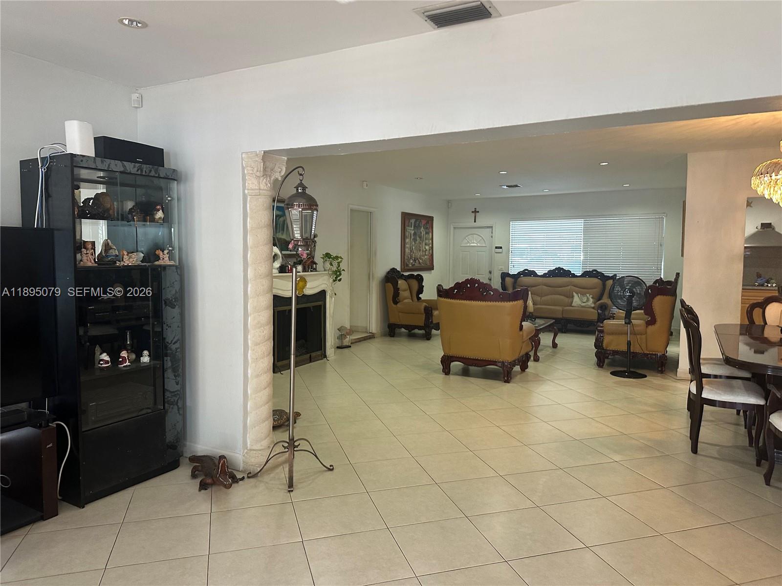A spacious living and dining area features tile flooring, a decorative column, and traditional furniture — 12941 Auralia Rd, North Miami FL 33181, NORTH MIAMI, FL