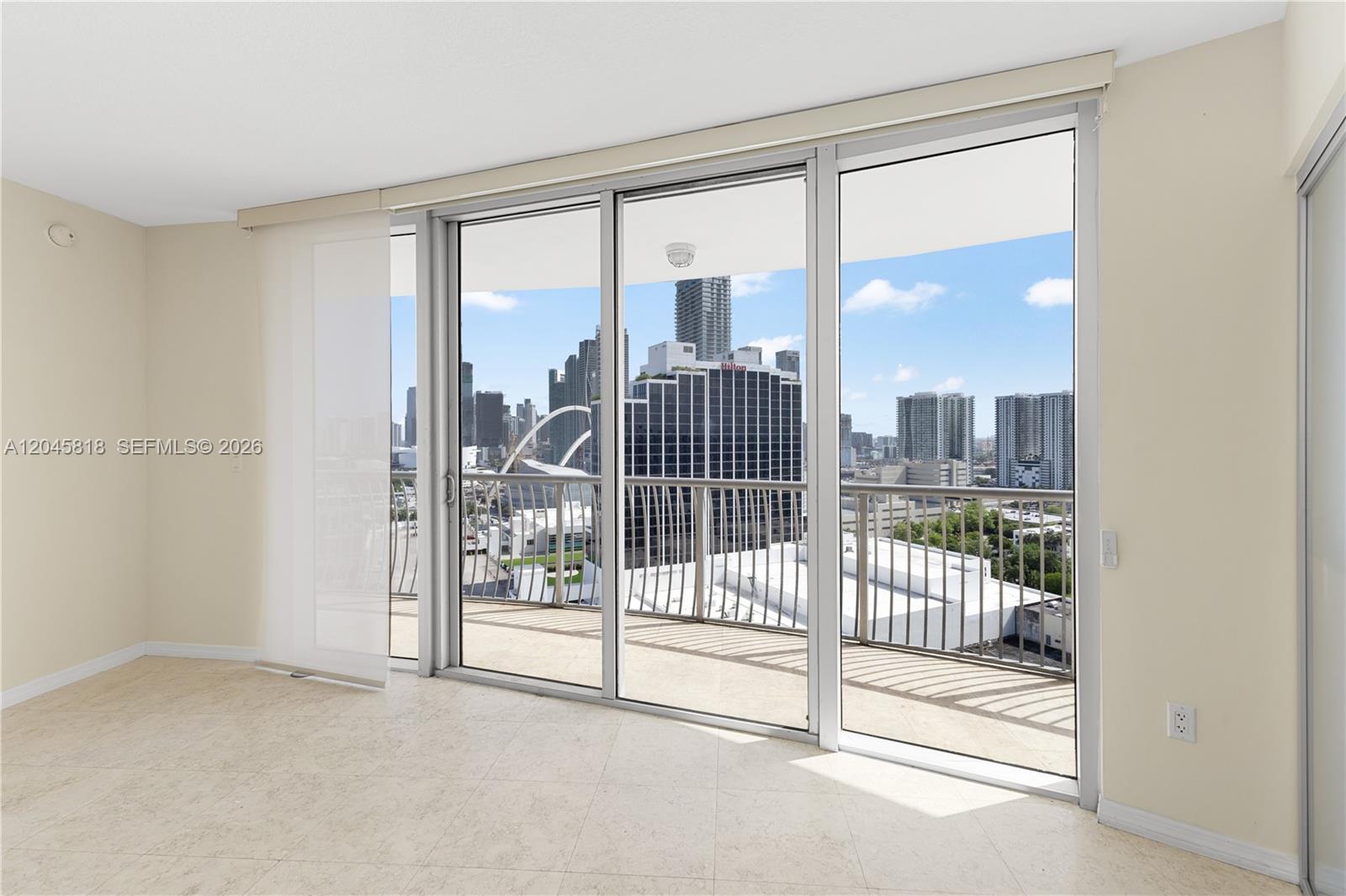 An empty room with light tile flooring features a large sliding glass door to a balcony — 1750 N Bayshore Dr # 2414, Miami FL 33132, MIAMI, FL