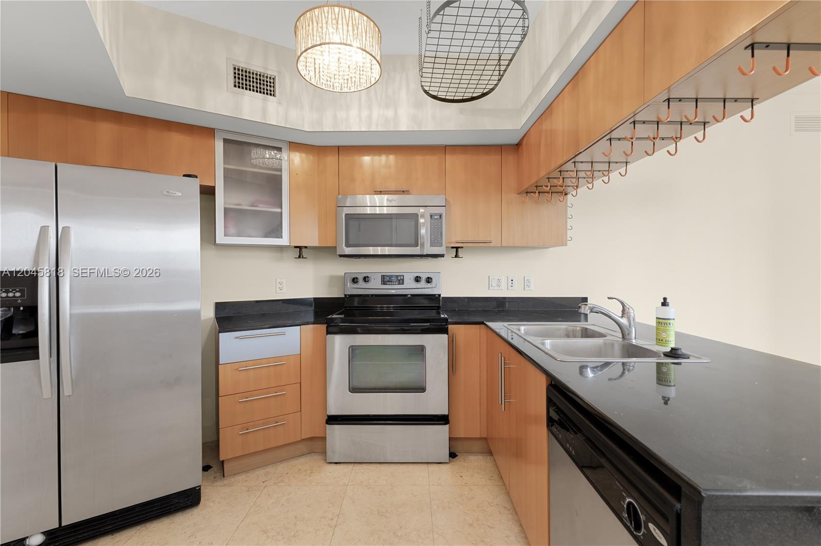 A kitchen features light wood cabinets, black countertops, stainless steel appliances, and a hanging rack — 1750 N Bayshore Dr # 2414, Miami FL 33132, MIAMI, FL