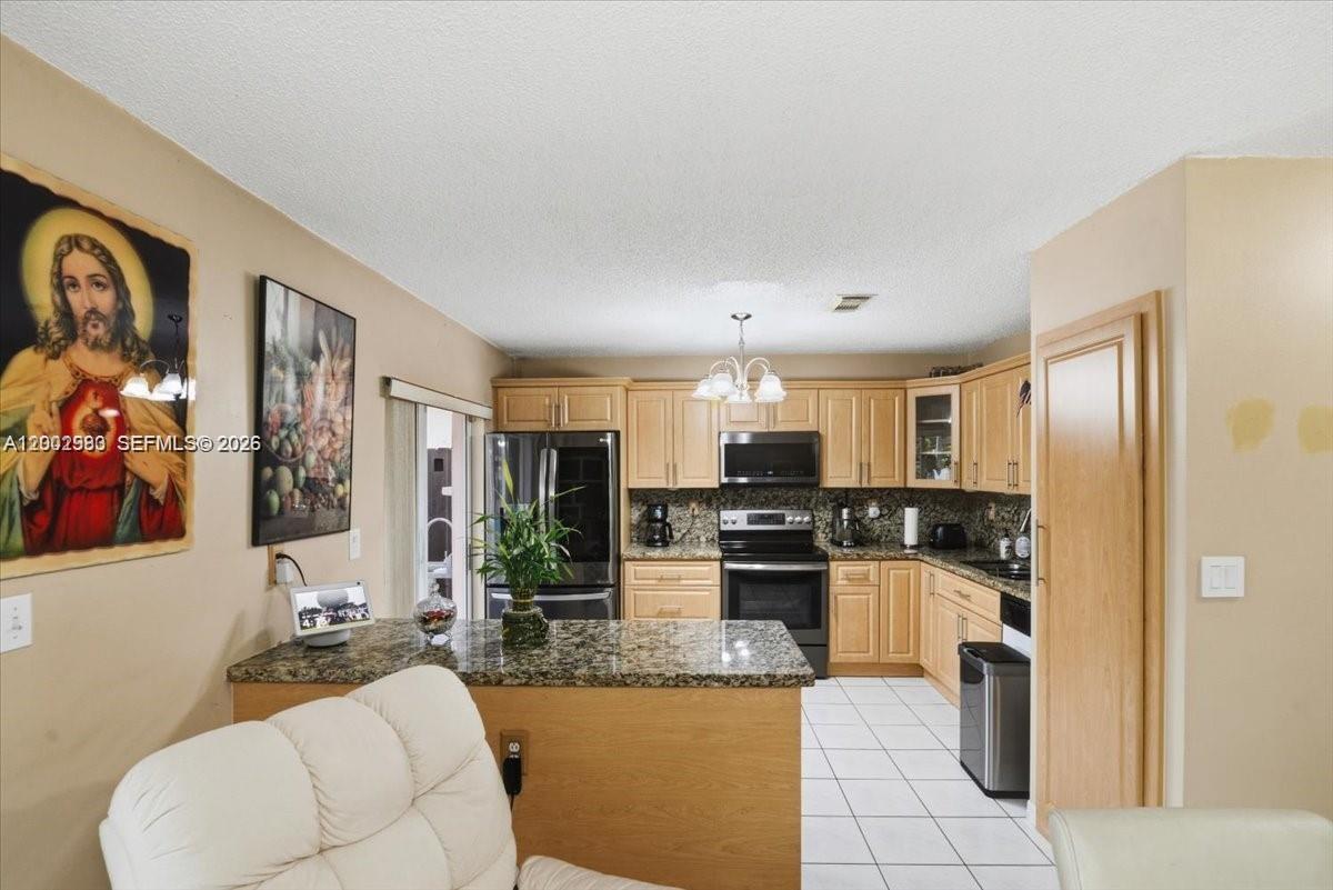 A kitchen features light wood cabinets, granite countertops, and a central island with seating — 13741 SW 160th Ter # 0, Miami FL 33177, MIAMI, FL