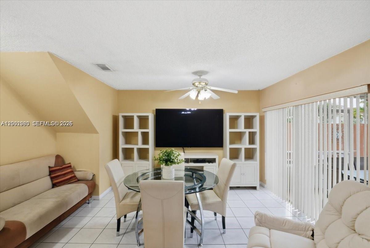 A dining room features a glass table, white chairs, a television, and tile flooring — 13741 SW 160th Ter # 0, Miami FL 33177, MIAMI, FL