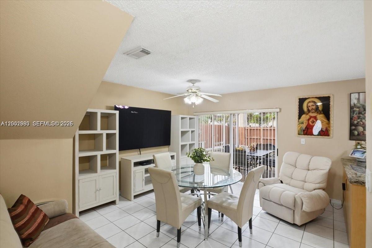 A living and dining area features a glass table, white shelving, and tile flooring — 13741 SW 160th Ter # 0, Miami FL 33177, MIAMI, FL