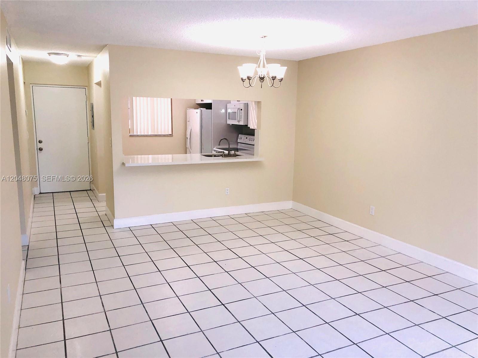 A dining area with white tiled floors features a pass-through window to the kitchen — 7830 Camino Real # K310, Miami FL 33143, MIAMI, FL