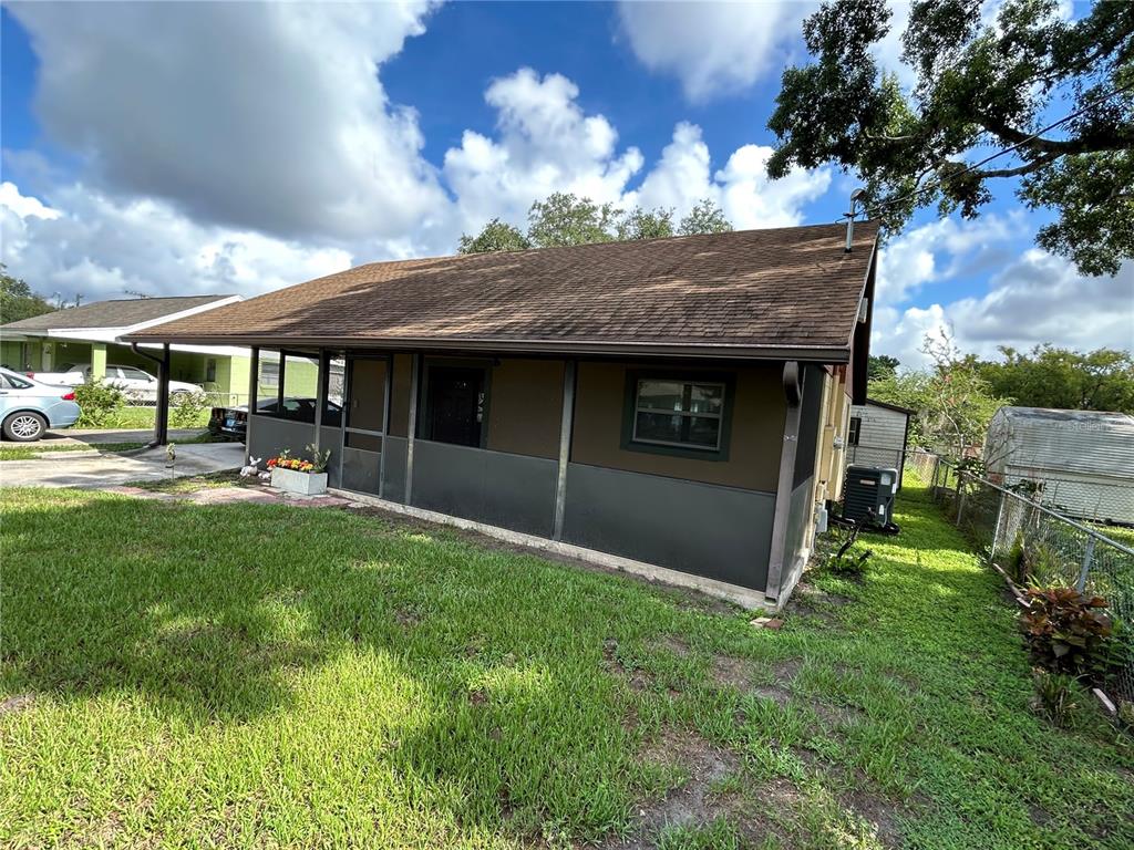 A single-story house with a brown shingled roof and a screened-in front porch — 1213 CHEROKEE DRIVE, KISSIMMEE, FL