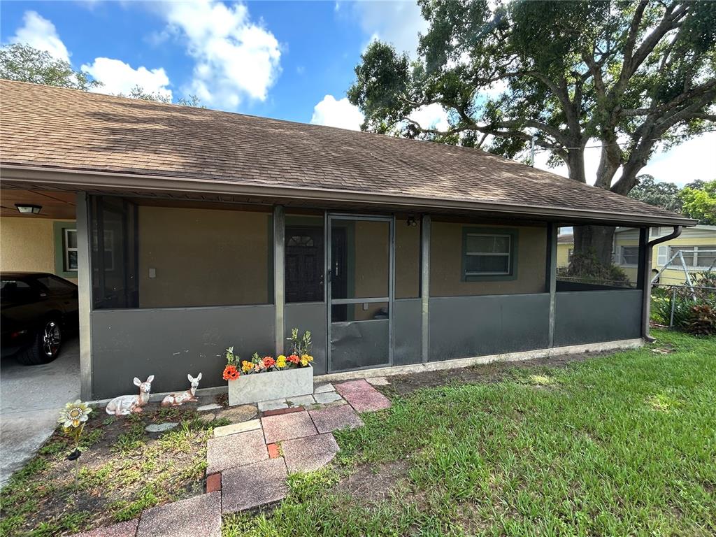 The exterior of a house features a screened-in porch, a shingled roof, and a walkway — 1213 CHEROKEE DRIVE, KISSIMMEE, FL