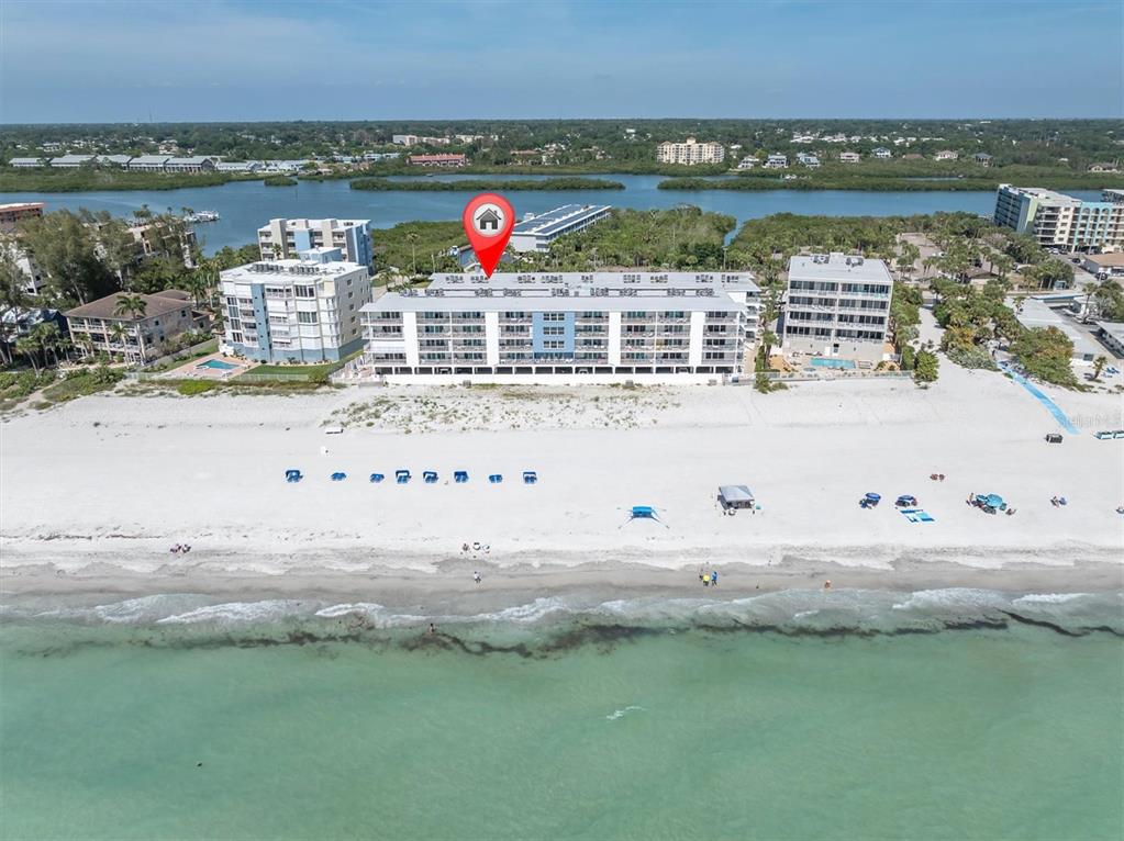 An aerial view of a multi-story beachfront condominium building on a sandy shore — 19610 GULF BOULEVARD UNIT 308, INDIAN ROCKS BEACH, FL