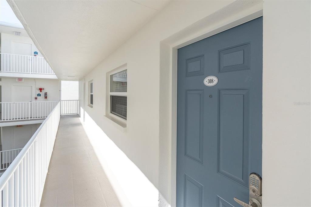 A blue apartment door numbered 308 is located on an outdoor concrete walkway — 19610 GULF BOULEVARD UNIT 308, INDIAN ROCKS BEACH, FL