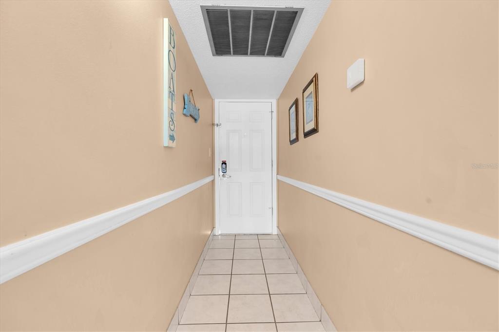 A narrow hallway features beige walls, white chair rail molding, and light-colored floor tiles — 19610 GULF BOULEVARD UNIT 308, INDIAN ROCKS BEACH, FL