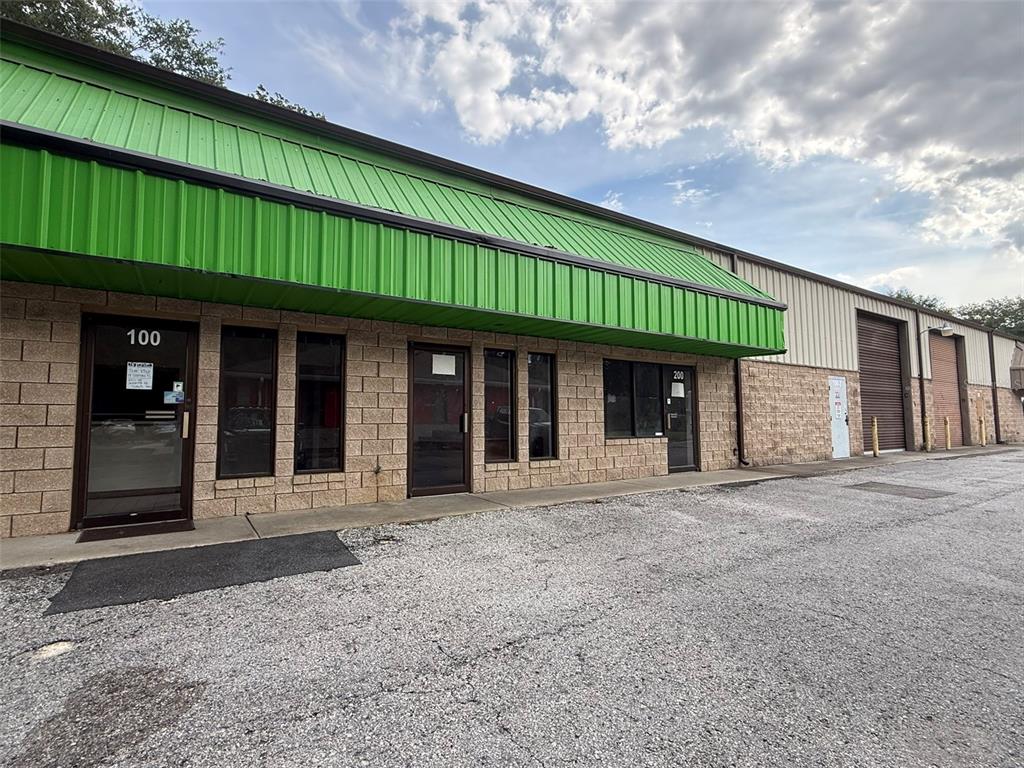 A commercial building exterior features a green metal awning and tan concrete block walls — 832 NW 30TH AVENUE UNIT 100 - 300, OCALA, FL