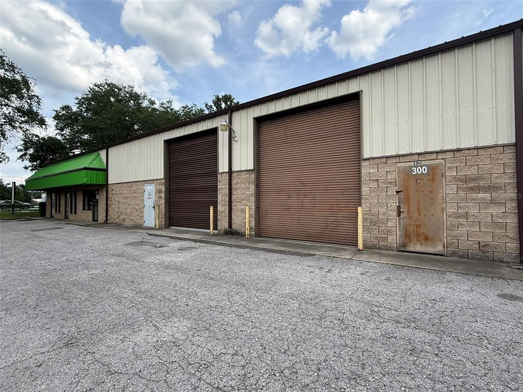 An exterior view of a commercial warehouse building with metal roll-up doors and brick siding — 832 NW 30TH AVENUE UNIT 100 - 300, OCALA, FL