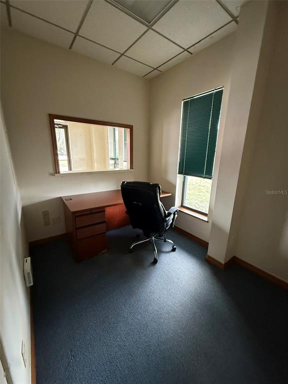 A small office features a wooden desk, a black rolling chair, and a window with blinds — 832 NW 30TH AVENUE UNIT 100 - 300, OCALA, FL