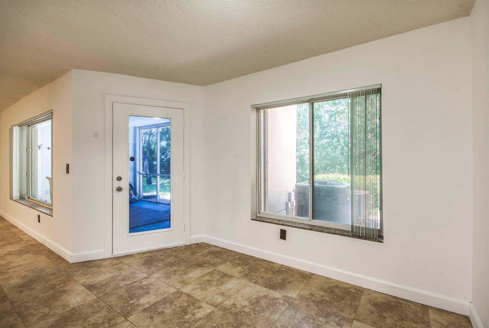 A room with tiled floors, white walls, a glass-paneled door, and a large sliding window — 815 W Boynton Beach Boulevard # 103, Boynton Beach FL 33426, BOYNTON BEACH, FL