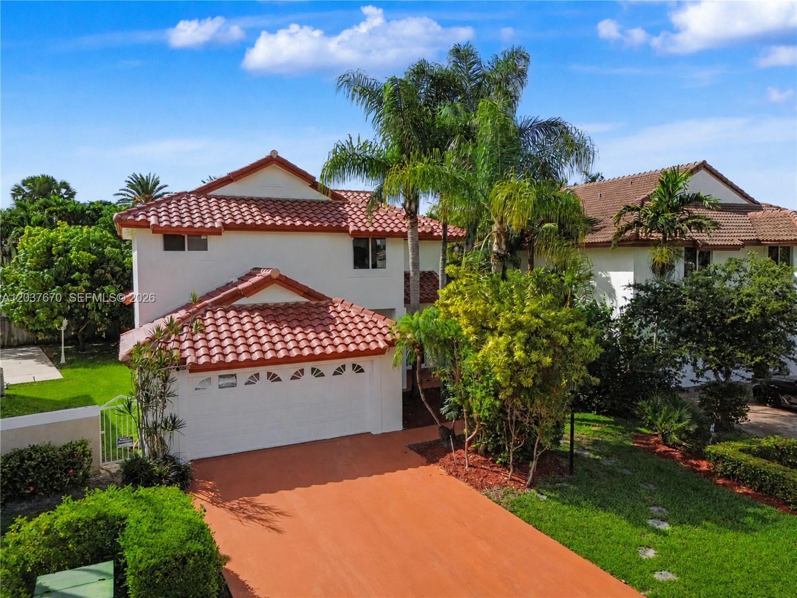 An exterior view of a two-story house with a red tile roof and driveway — 4725 NW 104th Ave, Doral FL 33178, DORAL, FL