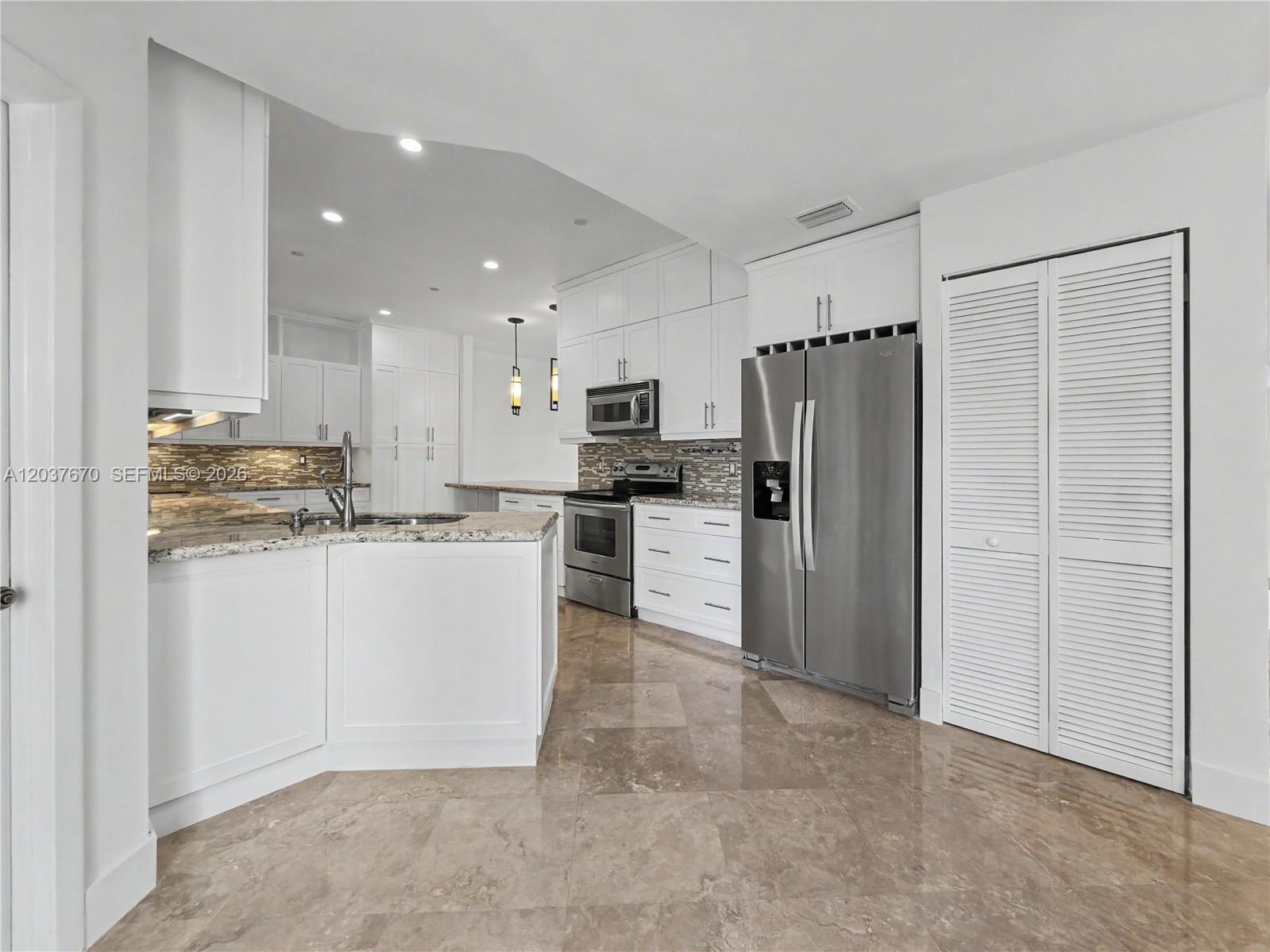 A kitchen features white cabinetry, stainless steel appliances, granite countertops, and light-colored tile flooring — 4725 NW 104th Ave, Doral FL 33178, DORAL, FL
