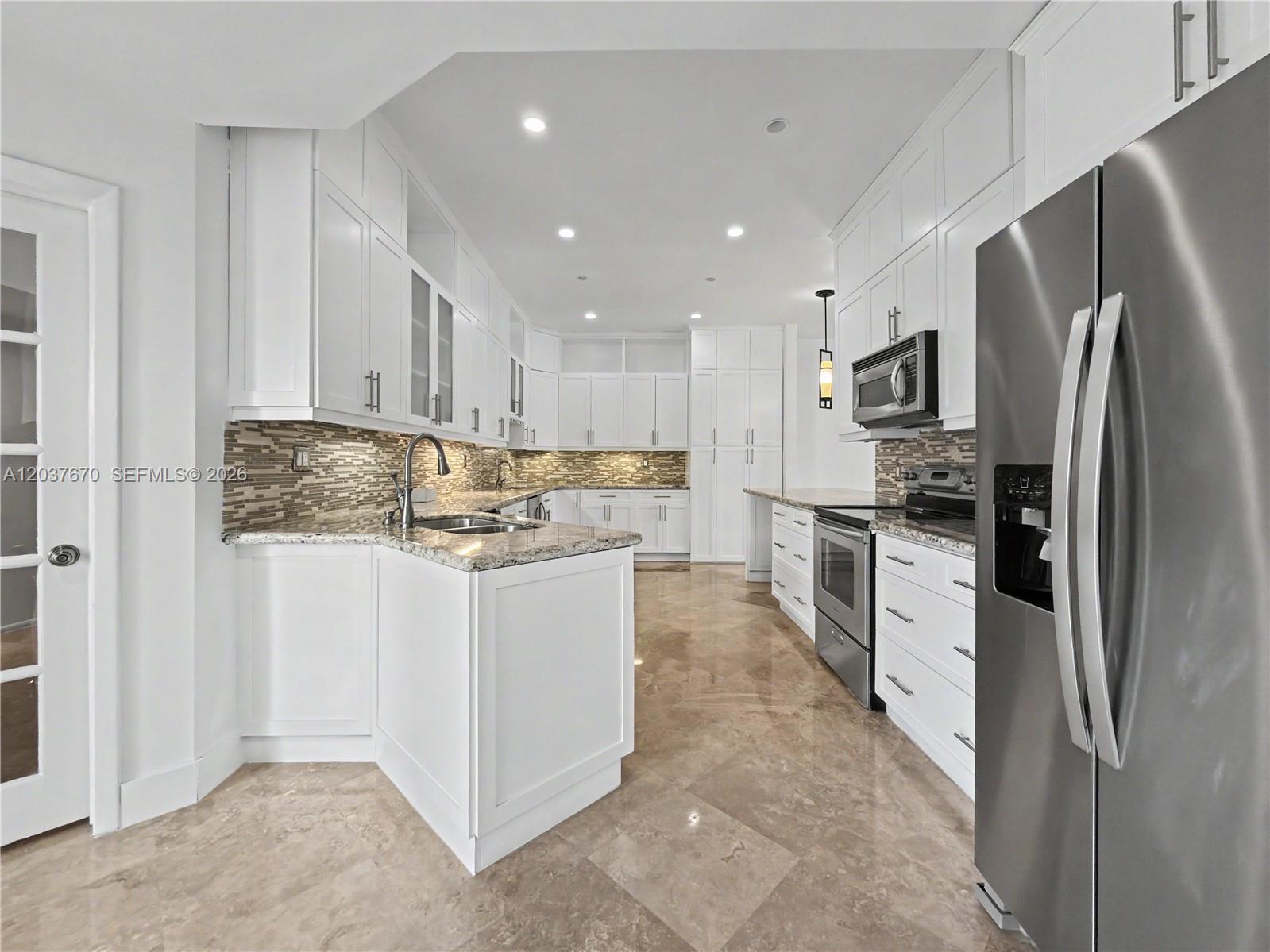 A white kitchen features granite countertops, stainless steel appliances, and light-colored tile flooring — 4725 NW 104th Ave, Doral FL 33178, DORAL, FL