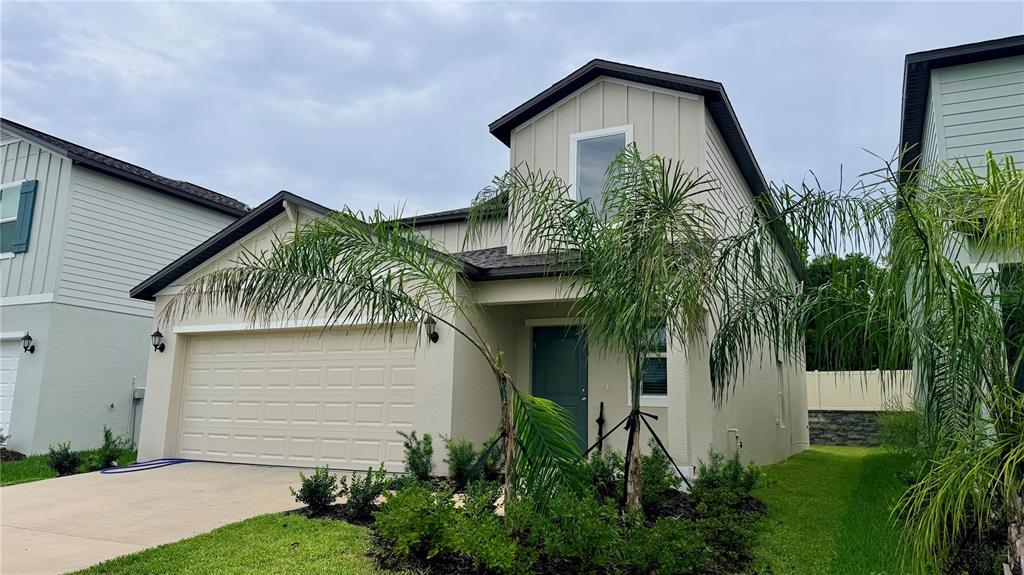 A two-story house with a beige exterior, a two-car garage, and a palm tree — 7727 ABAGAIL DRIVE, LAKELAND, FL