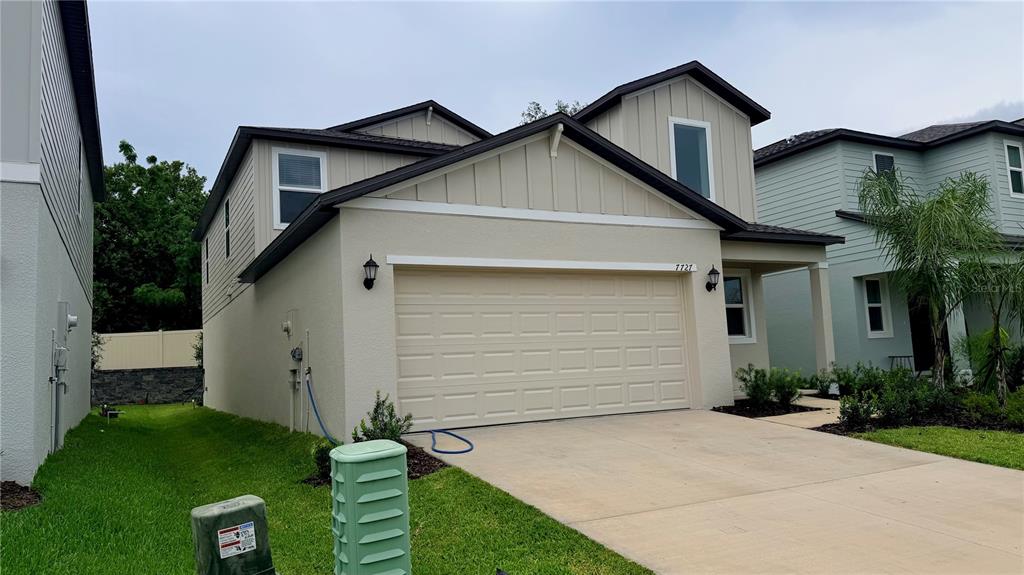A two-story house with a beige stucco exterior, a two-car garage, and a concrete driveway — 7727 ABAGAIL DRIVE, LAKELAND, FL