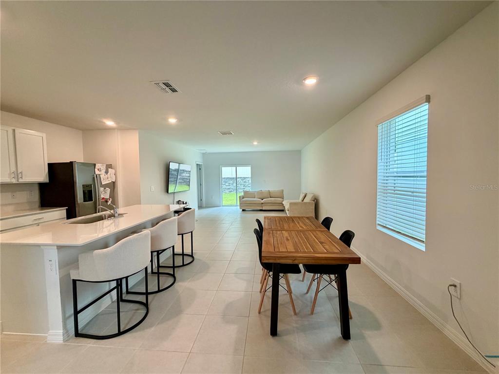 An open-concept kitchen with a breakfast bar and dining area leads to a living room — 7727 ABAGAIL DRIVE, LAKELAND, FL